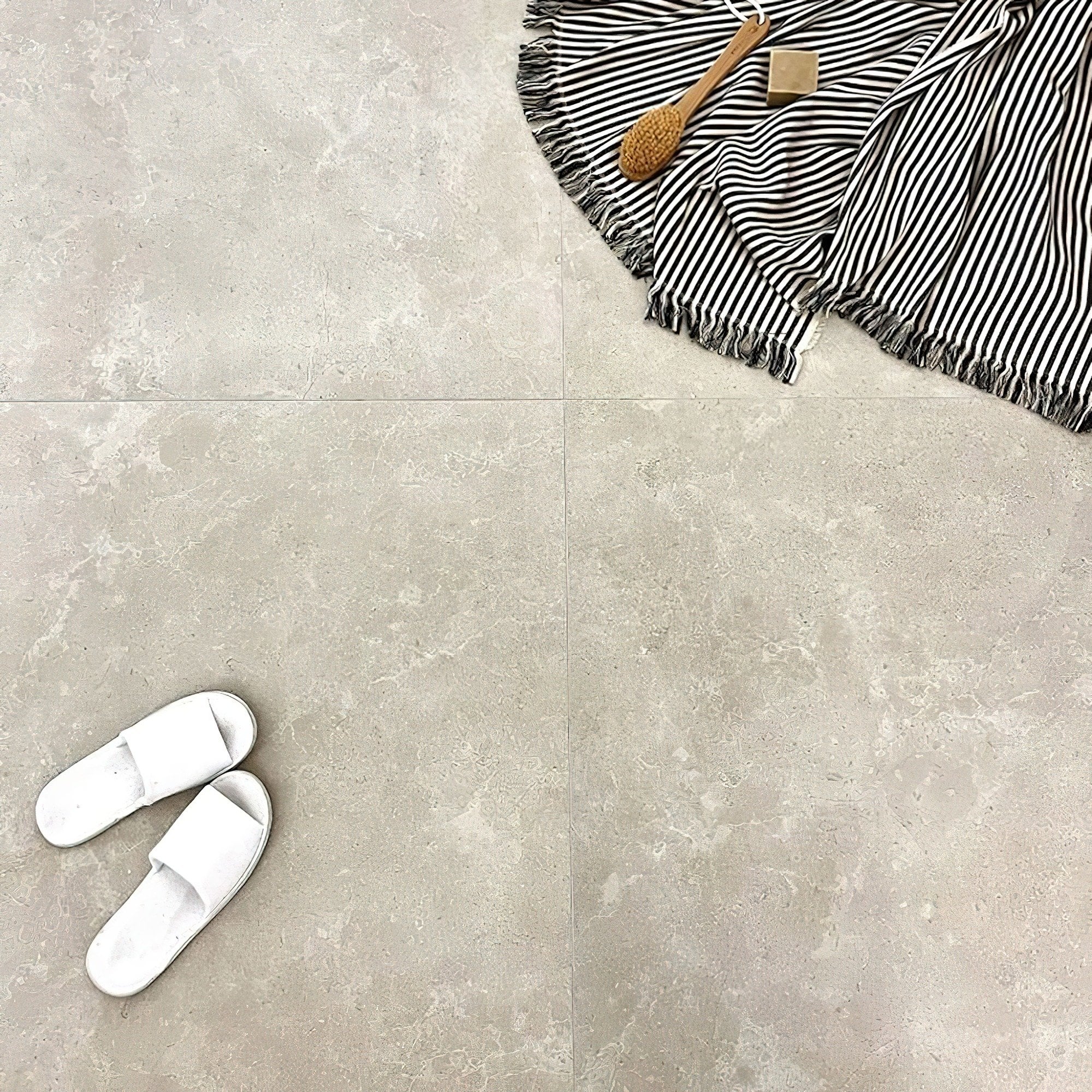 Floor view, straight down of Elche Limestone Hauteville Cream Porcelain Tiles with bathroom clothing on.